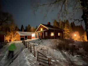 Norra Fjällets stuga i stjärnglans, siluett av en skidåkare anas i framkant